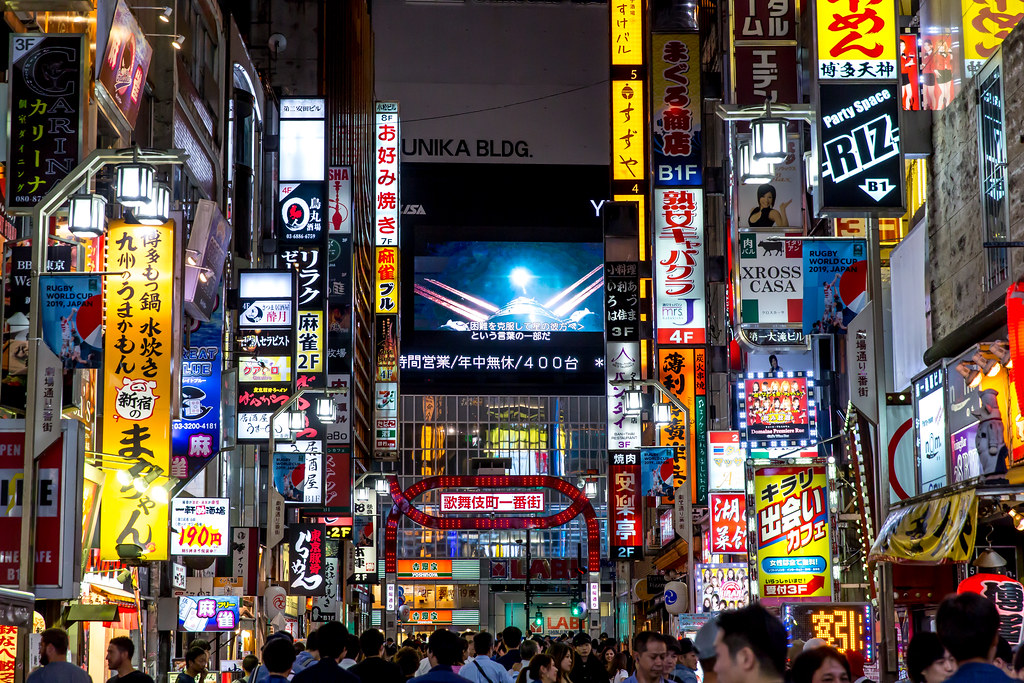 Bustling street in Tokyo with neon lights on billboards and people walking